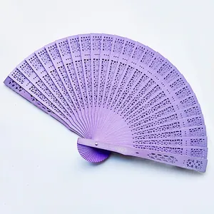 Macro view of purple hollow-carved wooden folding fan for wedding gift