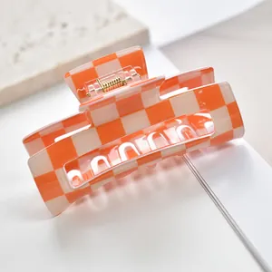 Macro view of orange checkerboard claw clip showing glossy finish and spring detail