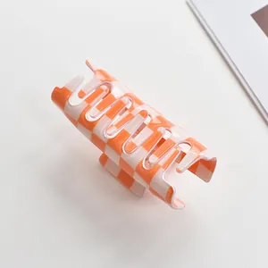 Detailed view of the orange and cream checkered pattern on a large square hair claw clip