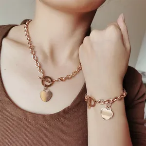 Vue détaillée de l'ensemble de bijoux en acier doré rose avec pendentif cœur et fermoir T