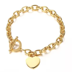 Gros plan d'un bracelet en acier inoxydable doré avec fermoir en T et pendentif cœur.