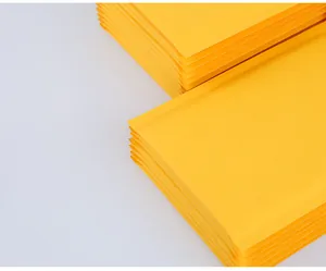 Detail view of stacked yellow kraft bubble mailers showing thick padding and smooth texture