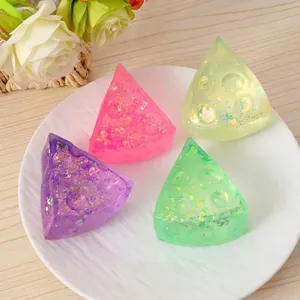 Macro di quattro giocattoli antistress a triangolo in gel glitterato su piatto bianco