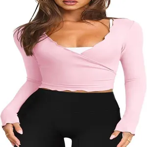 Detalle de top corto rosa de manga larga con cuello en V festoneado y cruzado.