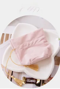 Detail view of pink velvet drawstring gift bag with elegant gold tassels