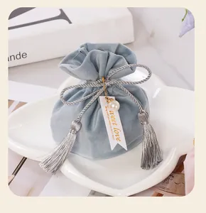 Detail view of a light blue velvet wedding favor bag with elegant silver tassels and tag