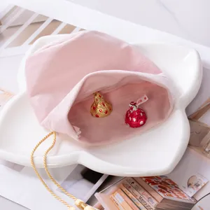 Pink velvet wedding candy drawstring bag with golden tassels on a white ceramic plate