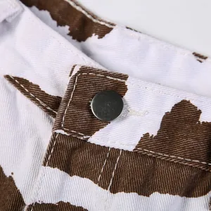 Detailansicht mit Metallknopf und braunem Kuhmuster-Denimstoff an Damenshorts