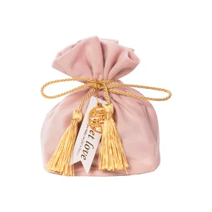 Elegant dusty pink velvet wedding favor bag with gold tassels and lucky charm ornament