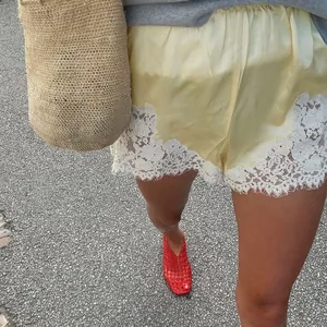 Vista dettagliata di pantaloncini in raso giallo con bordo in pizzo floreale bianco