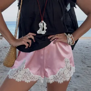 Primo piano di pantaloncini in raso rosa con dettagli in pizzo bianco rifiniti