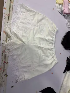 Dettaglio di pantaloncini bianchi a gamba larga con delicato bordo in pizzo floreale