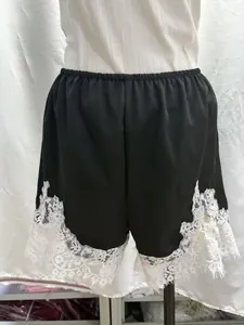 Dettaglio di pantaloncini in raso nero con bordo in pizzo floreale bianco