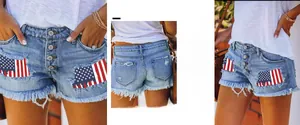 Detail view of distressed denim shorts with American flag patchwork and button-fly design.