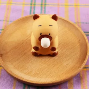 Close-up view of a cute Capybara squeeze toy blowing a bubble on a round wooden plate