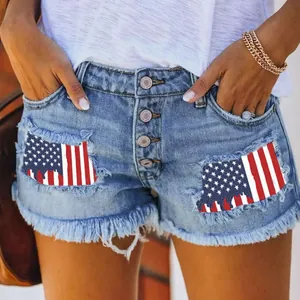 Detail of ripped denim shorts featuring American flag patches and a multi-button fly design