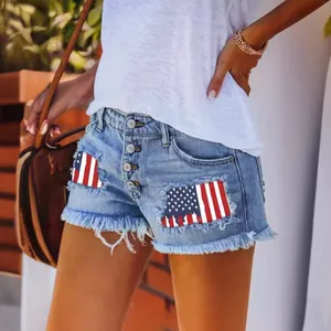 Detailed view of distressed denim shorts with American flag patches and button fly