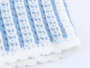 Détail d'un haut au crochet rayé bleu et blanc avec bordure festonnée