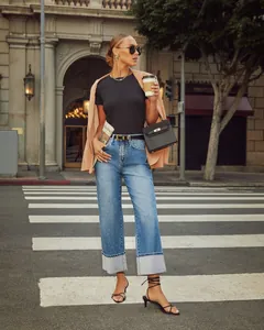 Detail view of high-waisted blue straight jeans with wide-cuffed hems in a city street setting