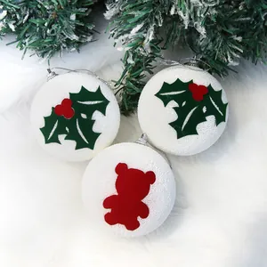 Dettaglio di palline di Natale bianche in schiuma con motivi orsetto e agrifoglio.