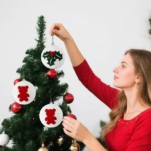 Palline di Natale bianche in schiuma con orsetti e motivi di agrifoglio su un albero.