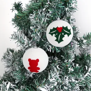 Primo piano di palline di Natale in schiuma bianca con motivi di orso e foglie di agrifoglio.