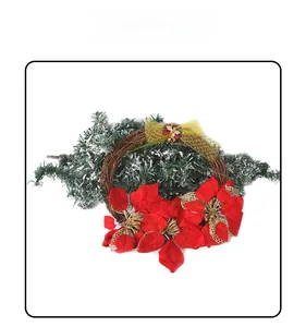 Detalle de corona de Navidad con flores rojas lazo dorado y ramas de pino