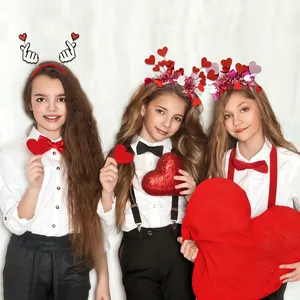 Three girls wearing various red heart headbands holding Valentine props for celebration