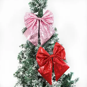 Grandi fiocchi di Natale con paillettes rosa e rossi che decorano un albero innevato