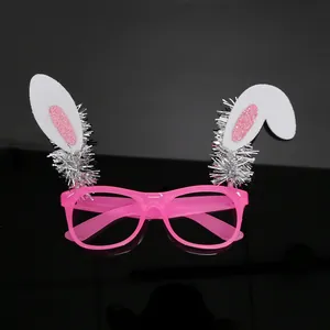 Primer plano de gafas de fiesta de conejo de Pascua rosas con espumillón sobre fondo negro
