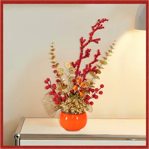 Festliche künstliche Blumen mit roten Beeren und Kakis in einem orangefarbenen Topf.