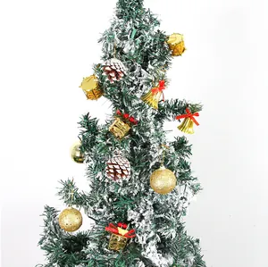 Detailansicht verschiedener goldener Weihnachtsglocken und Glitzerkugeln am verschneiten Baum