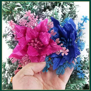 Glittery hot pink and blue artificial Christmas flowers held by hand for decoration