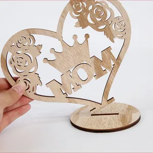 Detailed view of hollowed wooden Mother's Day heart ornament with MOM crown design