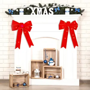 Détail de grands nœuds de Noël rouges lumineux à LED décorant une cheminée blanche