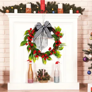 Corona de Navidad de vid con bayas rojas y lazo de cuadros en una chimenea blanca