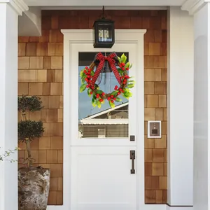 Corona de Navidad clásica con bayas rojas y lazo de cuadros en una puerta de entrada blanca