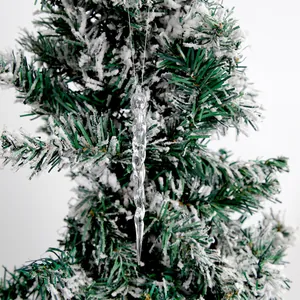 Primo piano di un ghiacciolo trasparente appeso a un ramo di albero di Natale innevato