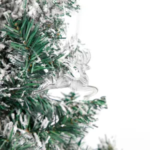 Primo piano di una decorazione a forma di renna trasparente su un albero di Natale innevato