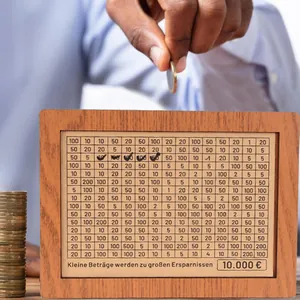 Close-up of a creative wooden money box featuring a detailed savings challenge counter grid