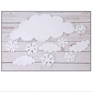 Detailed view of various white foam snowflake and cloud Christmas ornaments on wood