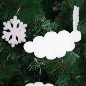 Macro view of white foam cloud and snowflake Christmas ornaments hanging on a green tree.