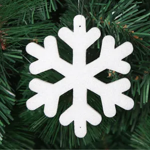 Close-up of a white textured foam snowflake ornament hanging on a green Christmas tree