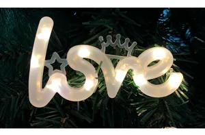 Detailopname van de LOVE LED-decoratielamp met kroon op groene dennentakken