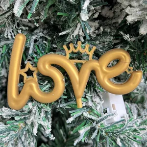 Close-up van gouden LOVE decoratief bord met kroon op besneeuwde kerstboomtakken