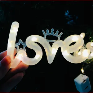 Detailopname van LOVE-vormige warme LED-lamp met decoratieve kroon en stermotief
