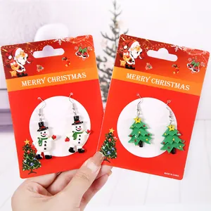 Orecchini festivi con pupazzo di neve e albero di Natale su cartoncini rossi regalo