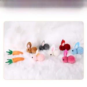 Close-up of colorful mini plush bunny and carrot hair clips on white fur background.