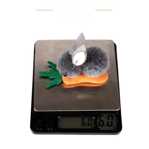 Detail shot of a 6g plush rabbit and carrot hair clip on a digital scale.