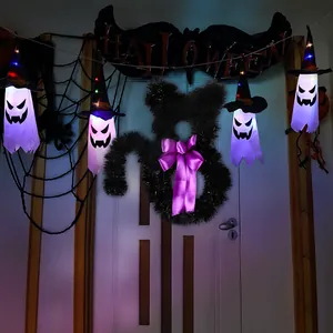 Detail view of glowing Halloween ghost pendants and a black cat tinsel wreath decoration
